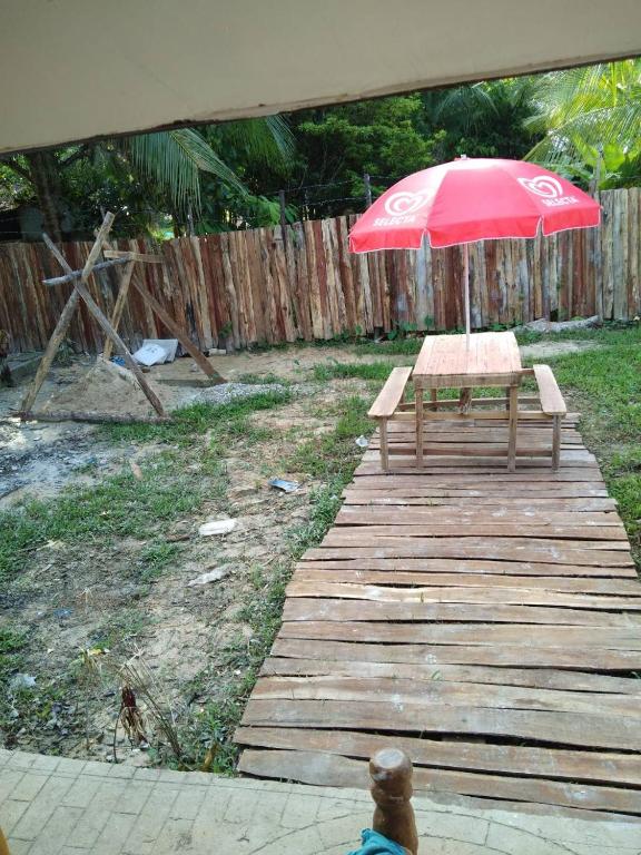 a picnic table with a red umbrella on a wooden deck at Nelmann's Nipa Huts in San Vicente