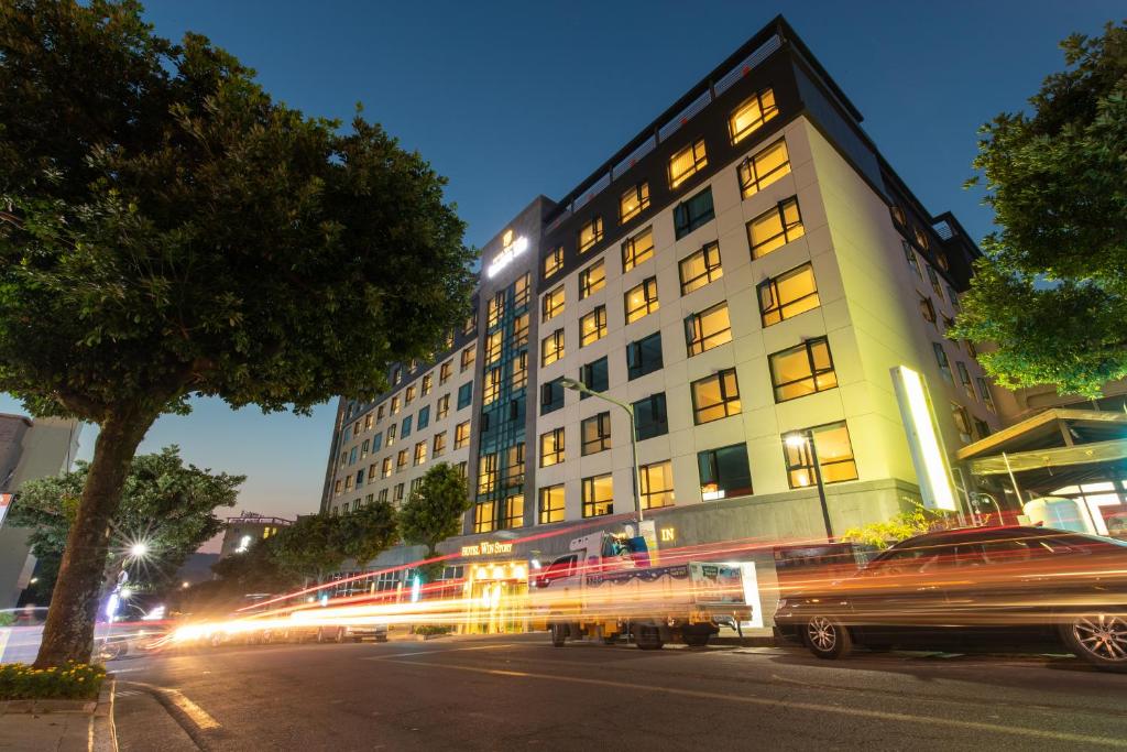 a building with a bus parked in front of it at Hotel Winstory in Seogwipo