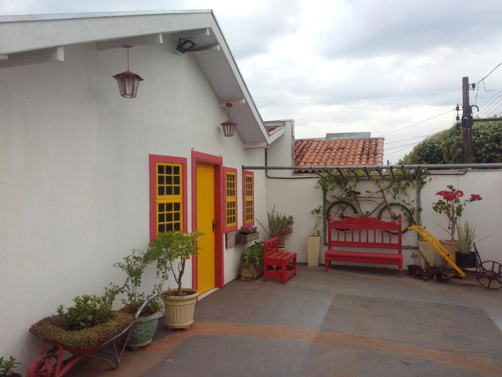 a white house with red doors and a red bench at Casa Camioto in Olímpia