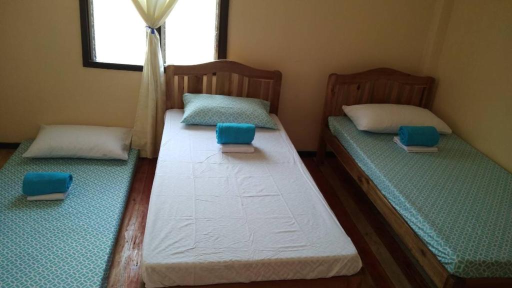 two beds in a room with blue pillows on them at Nelmann's Nipa Huts in San Vicente