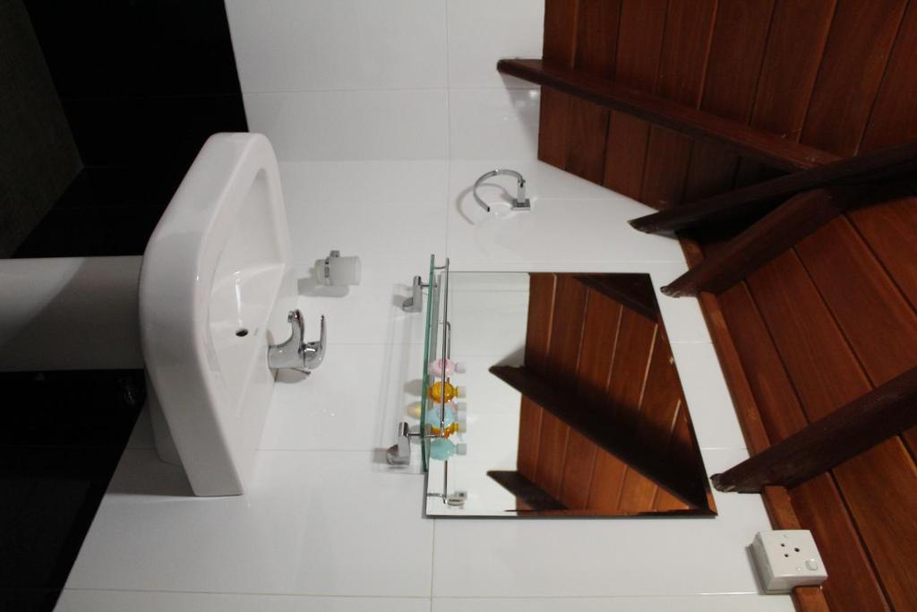 a white bathroom with a mirror and a sink at Dewdrops at Lake Gregory in Nuwara Eliya