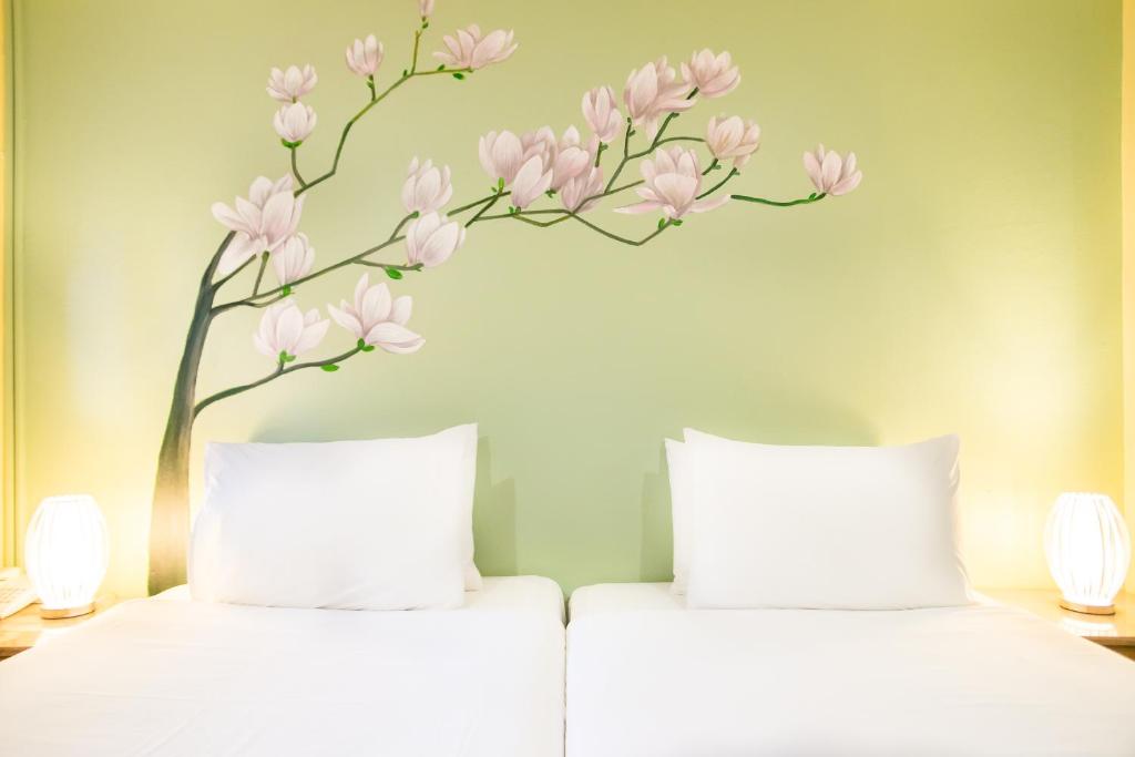 パタヤ・ノースにあるサワディー プレイスのベッド2台(ピンクの花の壁付)
