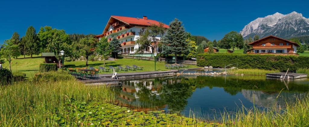 a hotel with a lake in front of a mountain at Landhotel Kielhuberhof in Ramsau am Dachstein
