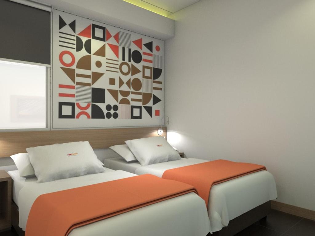 dwa łóżka w pokoju z obrazem na ścianie w obiekcie Front One Inn Kediri w mieście Kediri