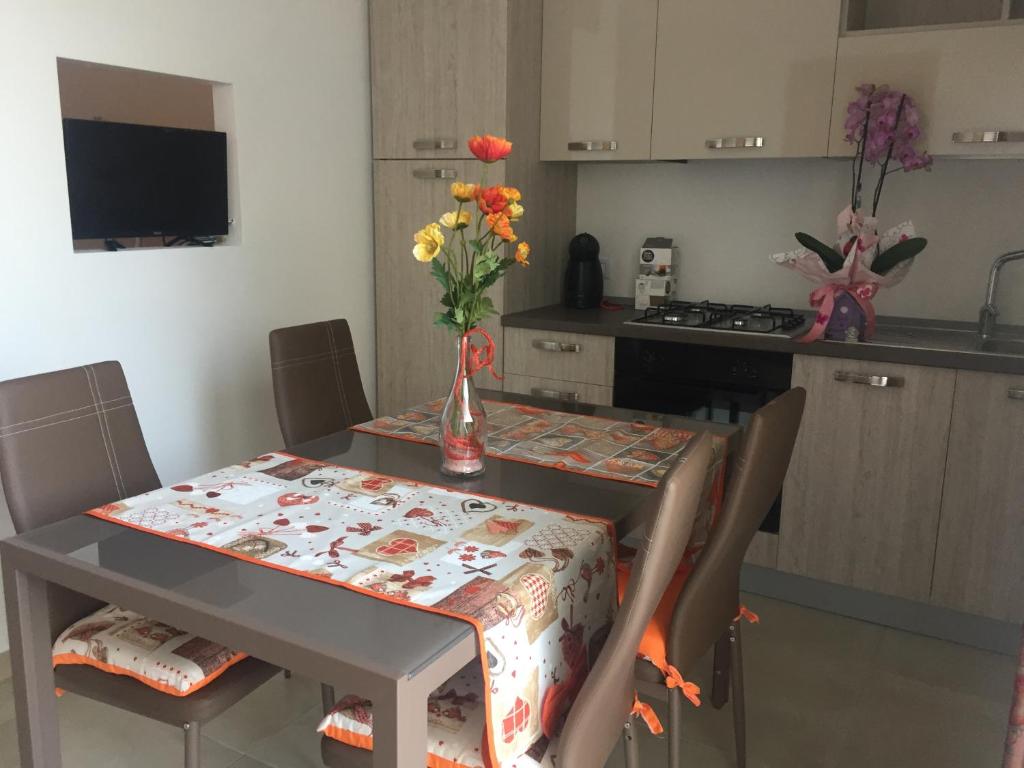 una cucina con tavolo e vaso di fiori di B & B L’ Aurora a Manduria