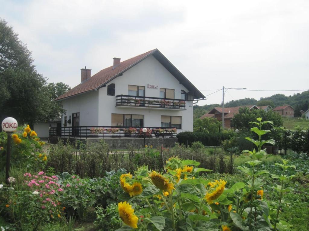 a white house with a garden in front of it at Sobe Zimmer Rooms Nika in Tušilović