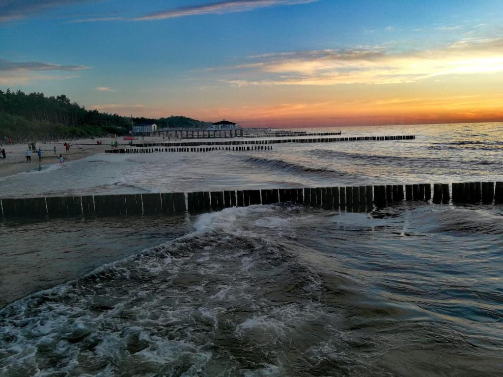 a beach with a pier and the ocean at sunset at Domki Letniskowe u Susła in Sianozety