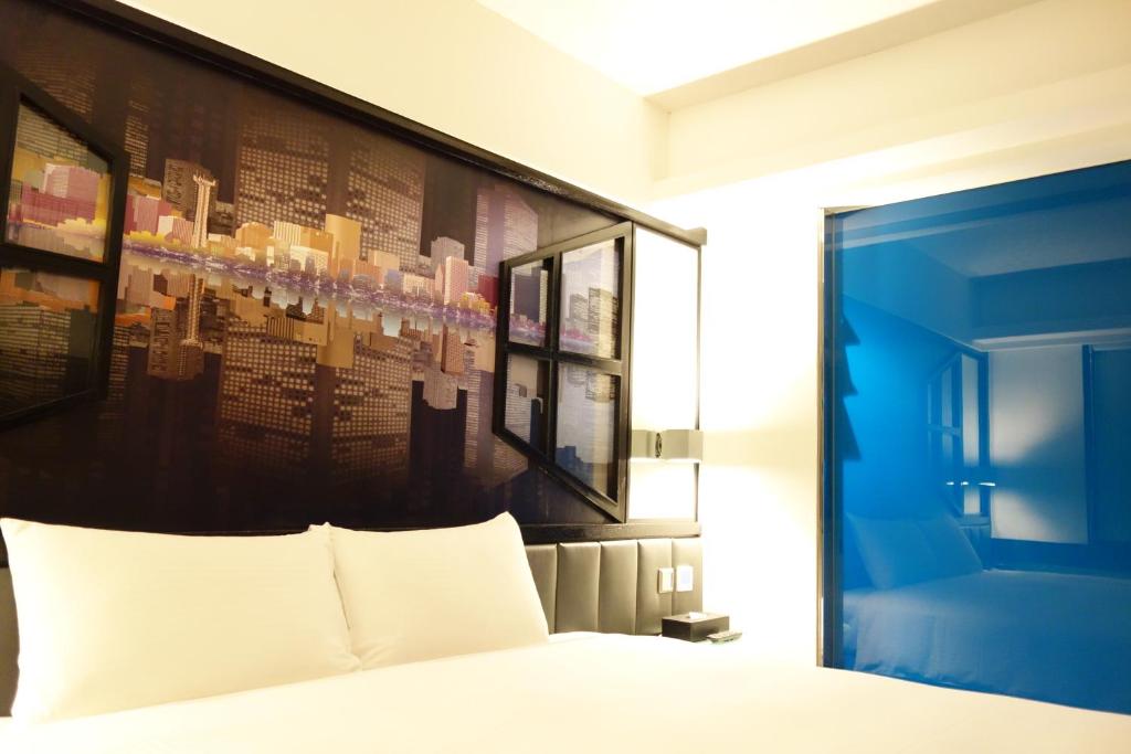 a bedroom with a bed and a wall with a painting at The Cloud Hotel in Kaohsiung