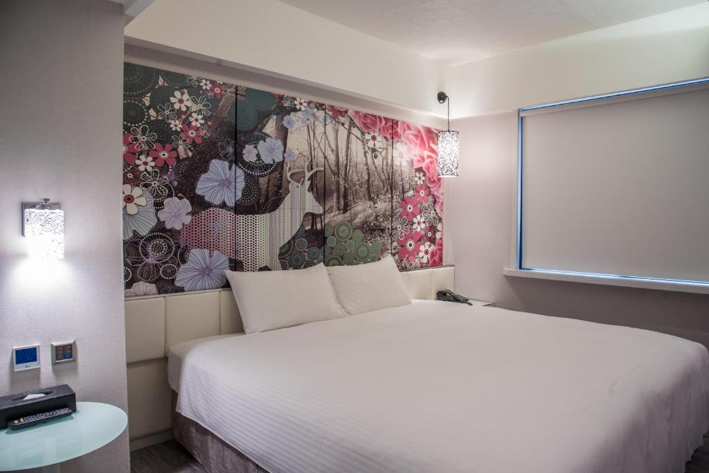 a bedroom with a large white bed and a wall mural at The Cloud Hotel in Kaohsiung