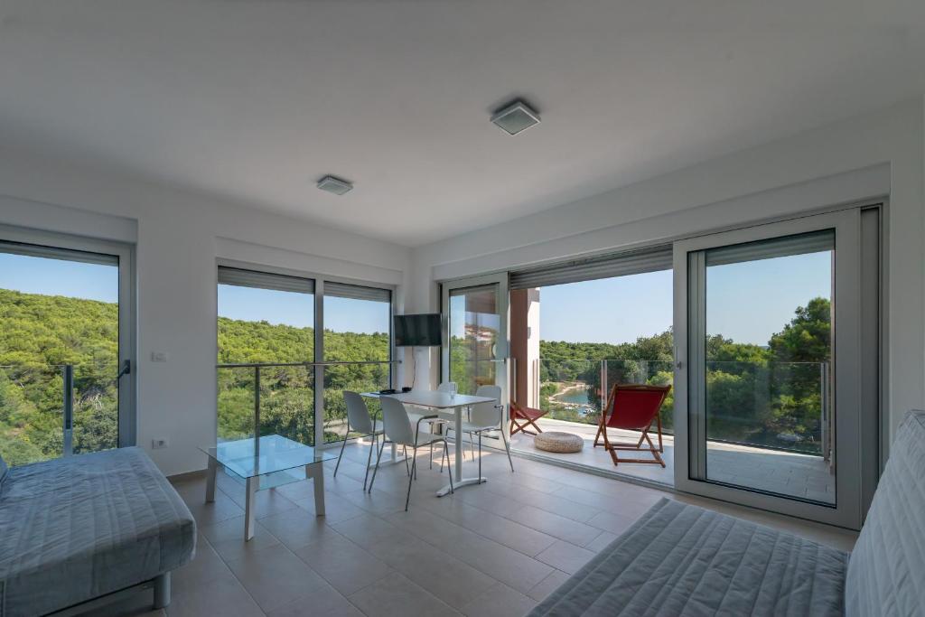 a living room with a table and chairs and windows at Premantura Resort - Hotel & Restaurant in Premantura