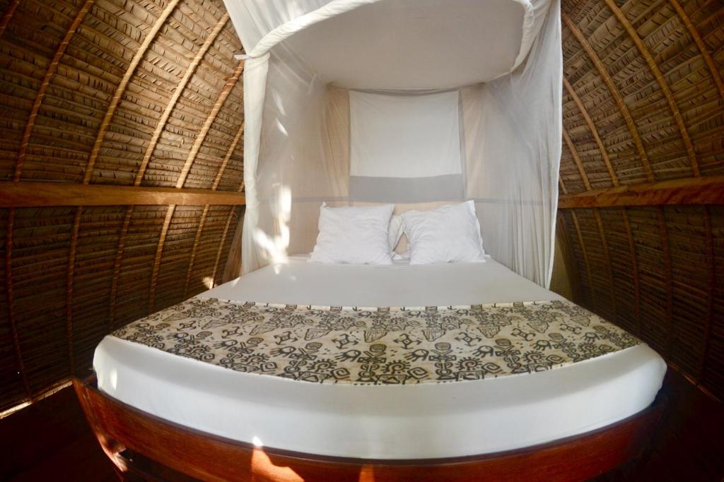 Cama pequeña en habitación con techo de paja y cama doble en Chez Nath en Isla Santa María