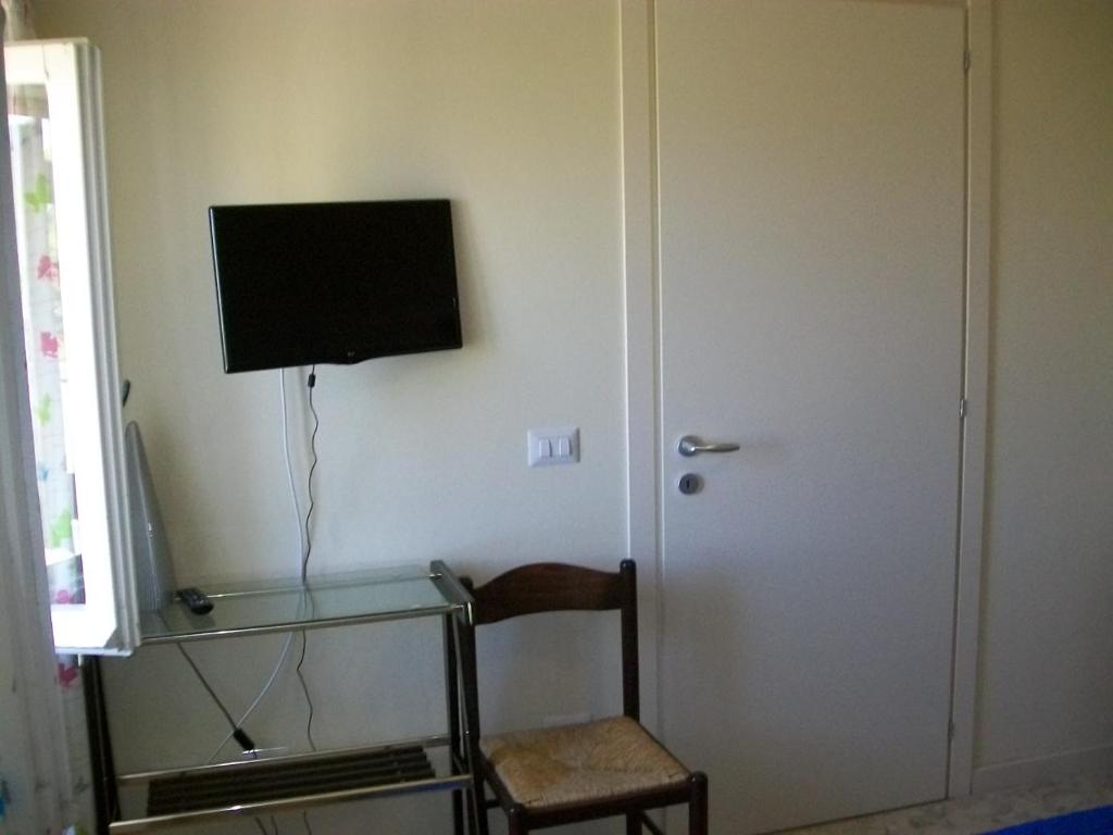 una stanza con una sedia e una televisione sul muro di Affittacamere il girasole a Recanati