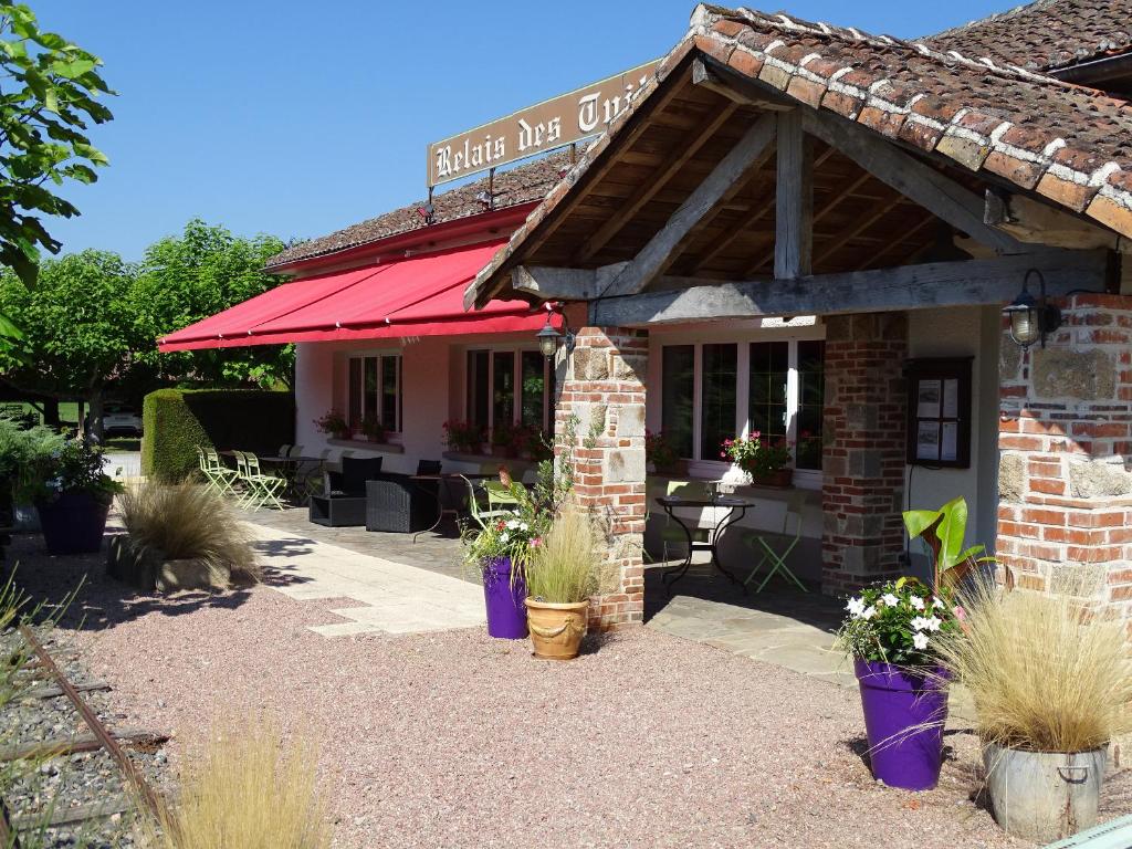 a restaurant with a red awning and plants in pots at le Relais des Tuileries in Séreilhac