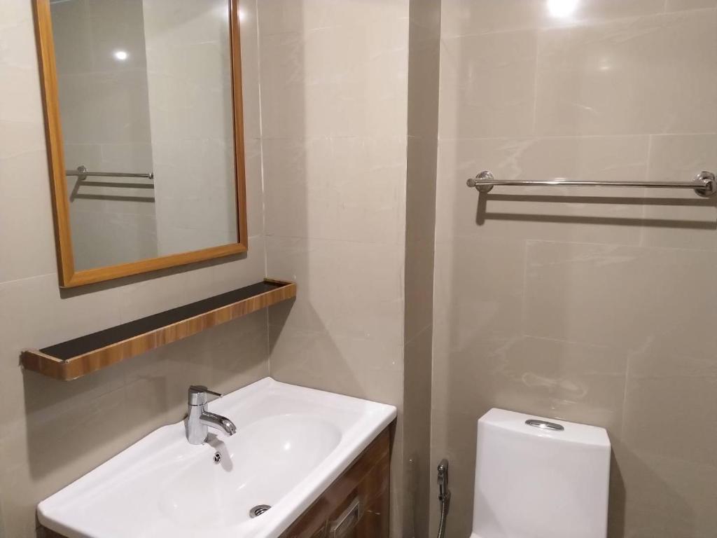 a bathroom with a sink and a mirror and a toilet at Roseate Bangkok Hotel in Bangkok
