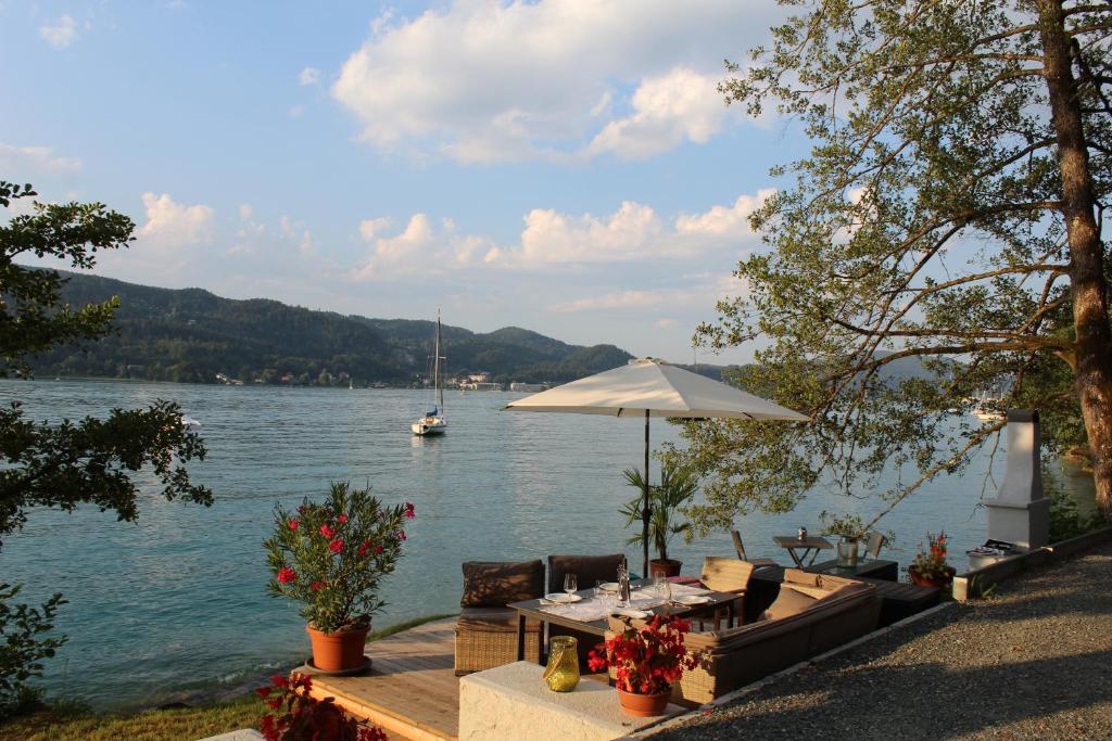 a table with an umbrella next to a body of water at Kusternighof in Velden am Wörthersee