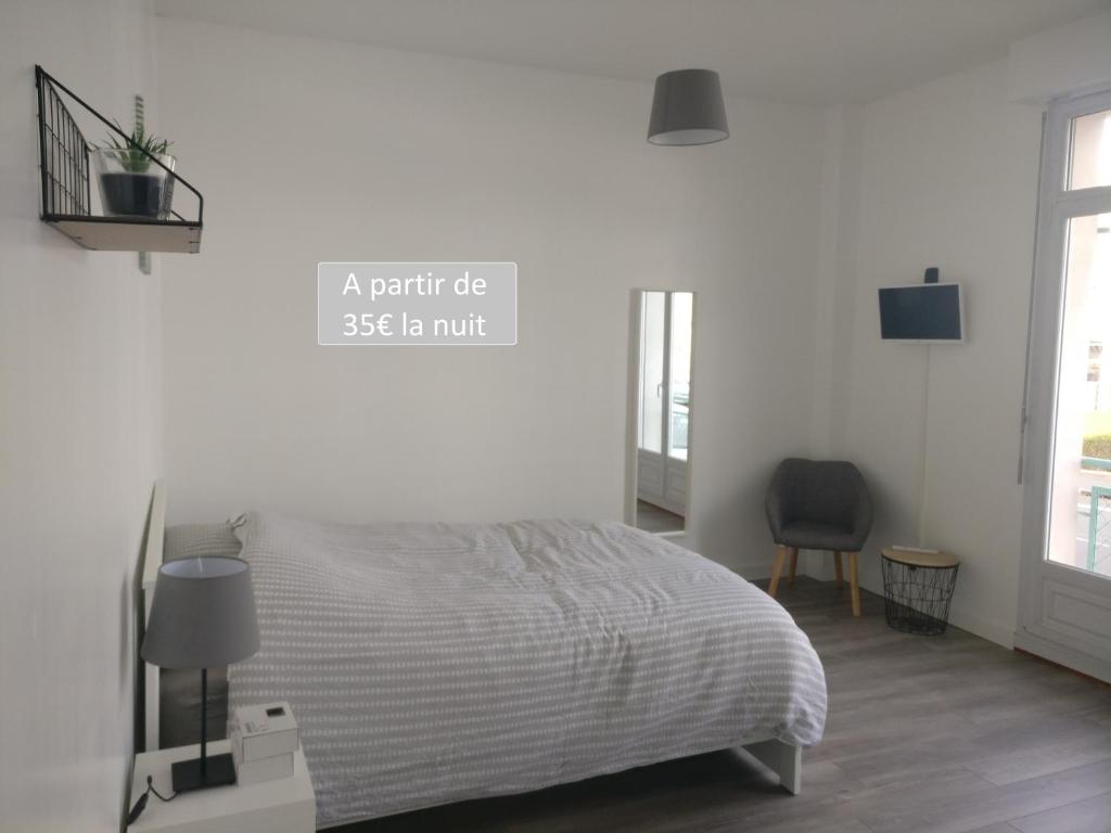 a white bedroom with a bed and a chair at Appart Hôtel L'Angélique in Saint-Nazaire