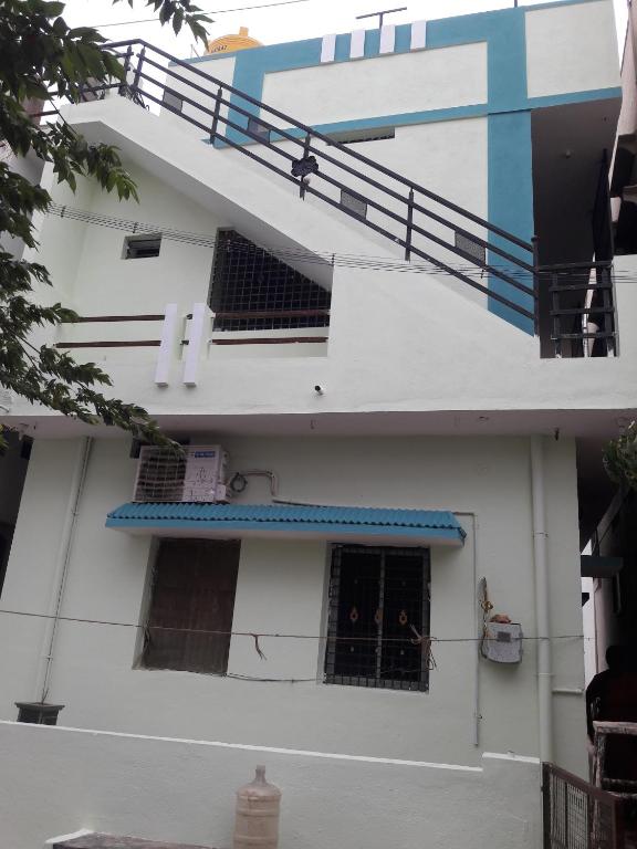 a white building with a staircase and a window at Rks Homestay in Hampi