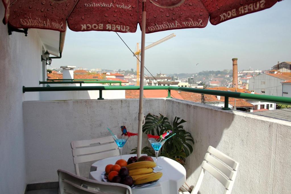 einen Tisch mit Obst auf einem Balkon mit Sonnenschirm in der Unterkunft Pretty house close to metro and wine cellars - host 8 in Vila Nova de Gaia
