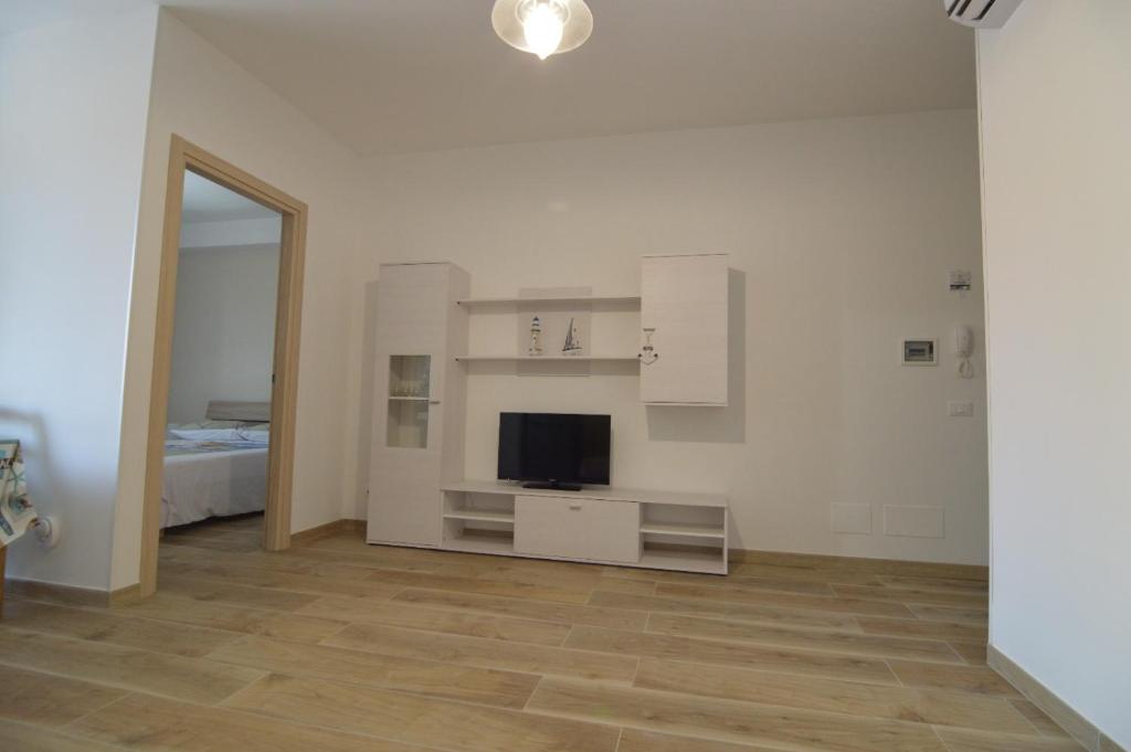 Habitación blanca con TV y dormitorio en Triscele Casa Vacanze, en Portopalo di Capo Passero