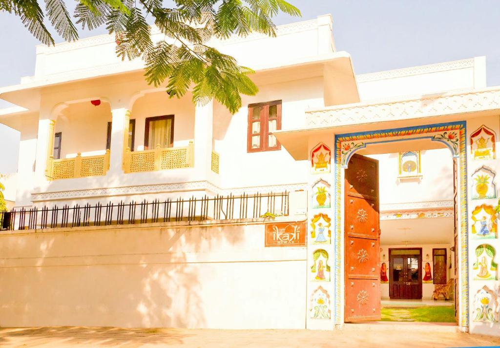 a white house with a gate and a palm tree at Ikaki Niwas - A Heritage Boutique Hotel in Jaipur