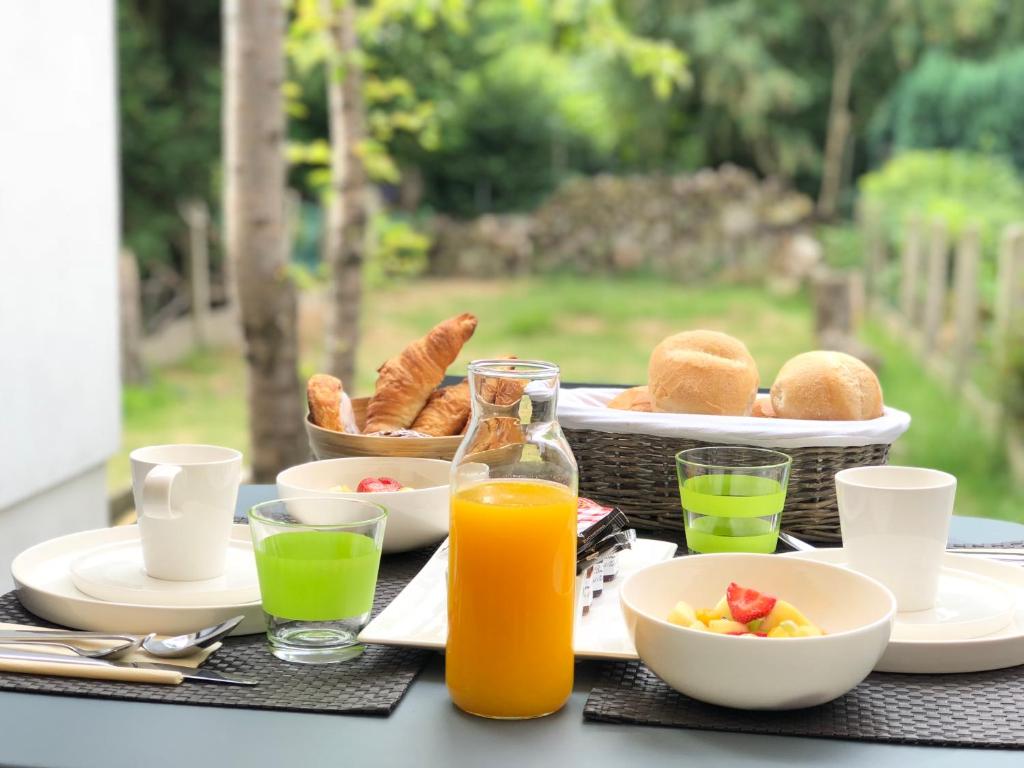 a breakfast table with a basket of food and orange juice at B&B Garden55 in Mechelen