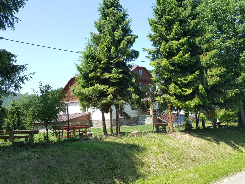 a park with benches and trees in front of a house at Cicha Dolina in Cisna