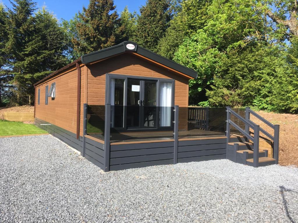 eine Hütte mit einer Veranda und einer Terrasse in der Unterkunft Atlas Ovation Lodge in Auchterarder