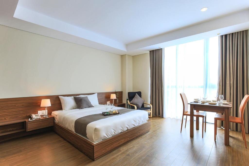 Una habitación de hotel con una cama, un escritorio y una mesa. en Aurora Serviced Apartments, en Ho Chi Minh