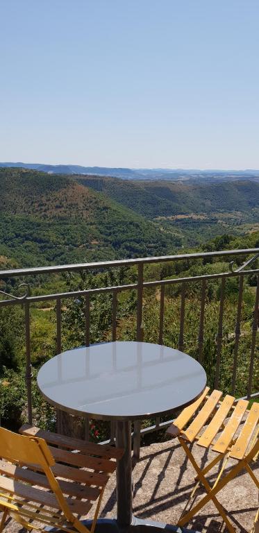 une table blanche et des chaises sur un balcon avec vue dans l'établissement La Petite Maison des Artistes, à Castelnau-Pégayrols