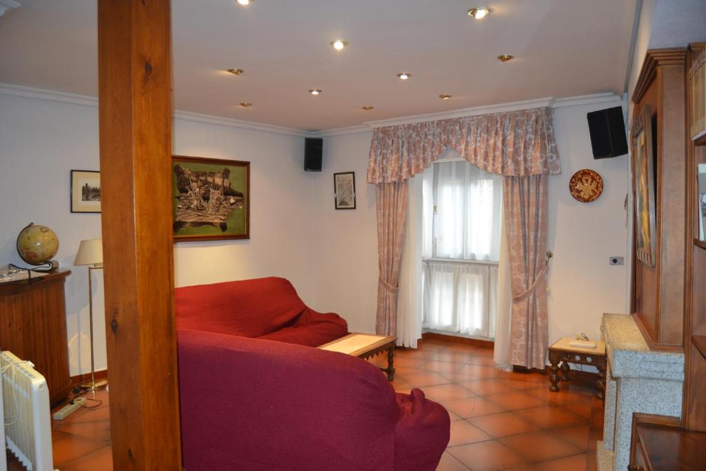 Una sala de estar con un sofá rojo y una ventana. en Casa Santo Tomé, en Toledo