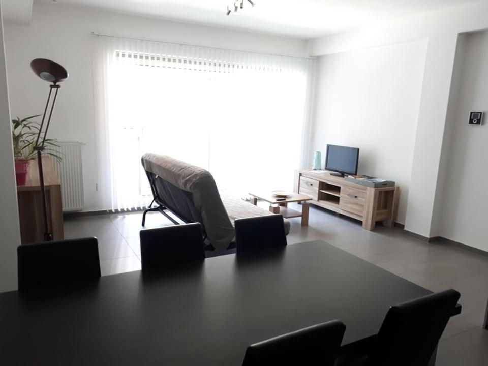 ein Wohnzimmer mit einem Tisch, Stühlen und einem TV in der Unterkunft Residentie Koen in Ostende