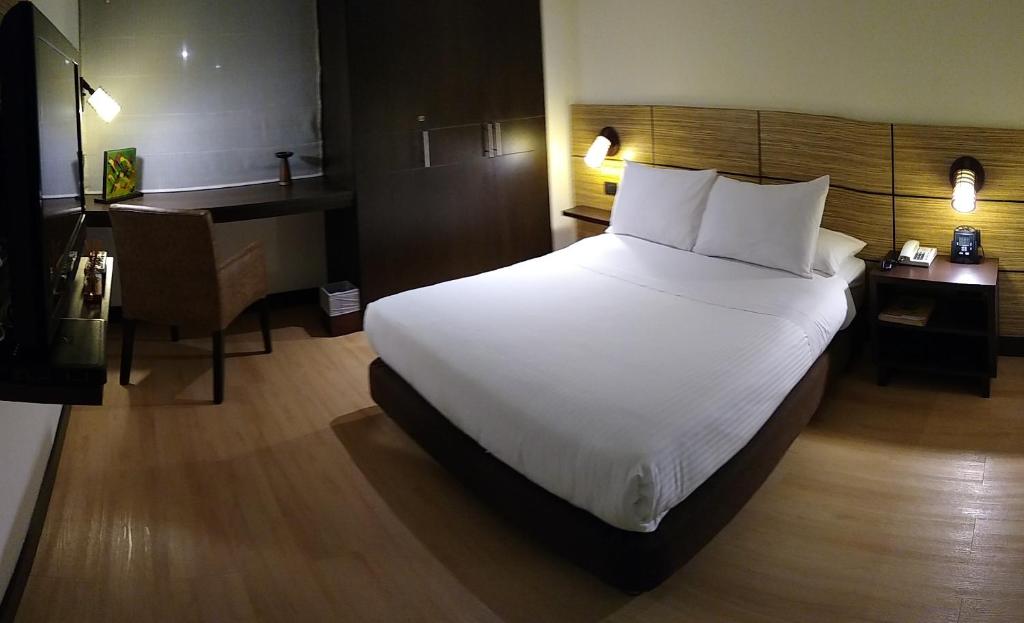 a bedroom with a large white bed and a desk at Scala 68 in Bogotá