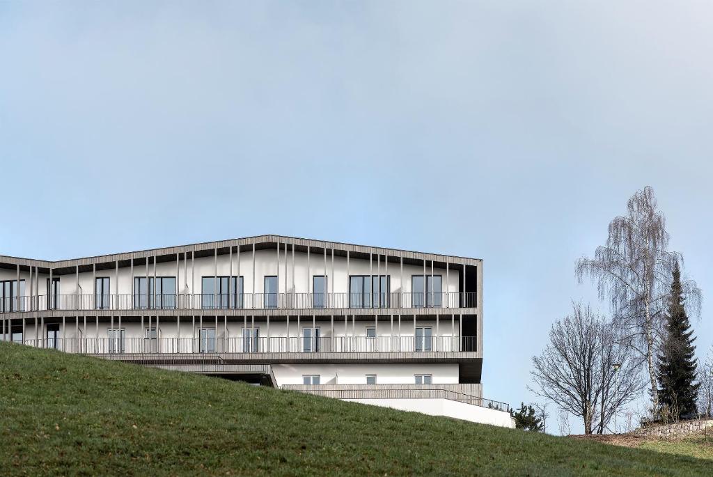 a building on top of a grassy hill at Hotel Lichtenstern in Soprabolzano