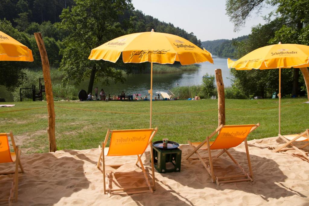 Country Camping Berlin في Tiefensee: مجموعة من الكراسي والمظلات في الرمال