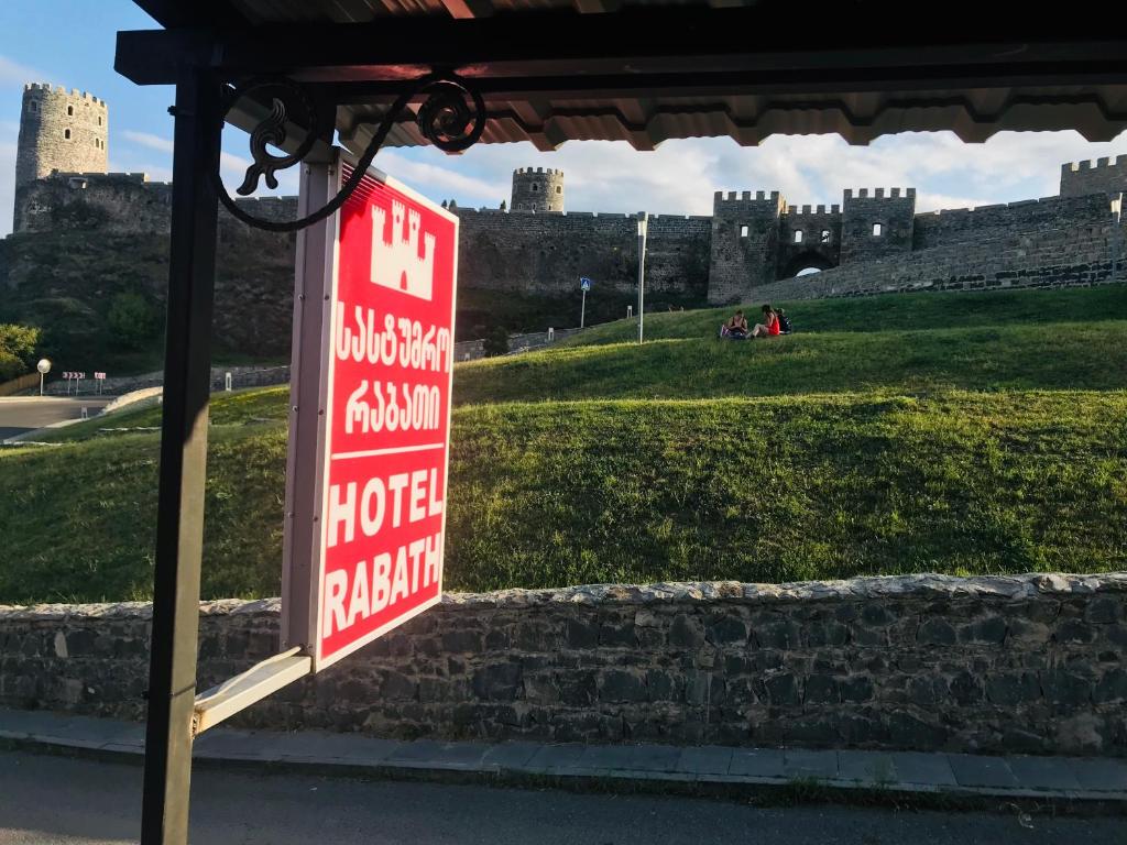 a sign for a hotel with a castle in the background at Hotel Rabath in Akhaltsikhe