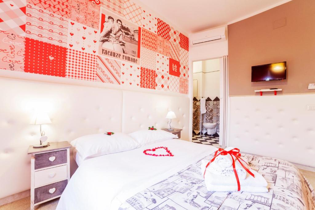 a bedroom with a white bed with a red bow on it at I Love Piramide in Rome