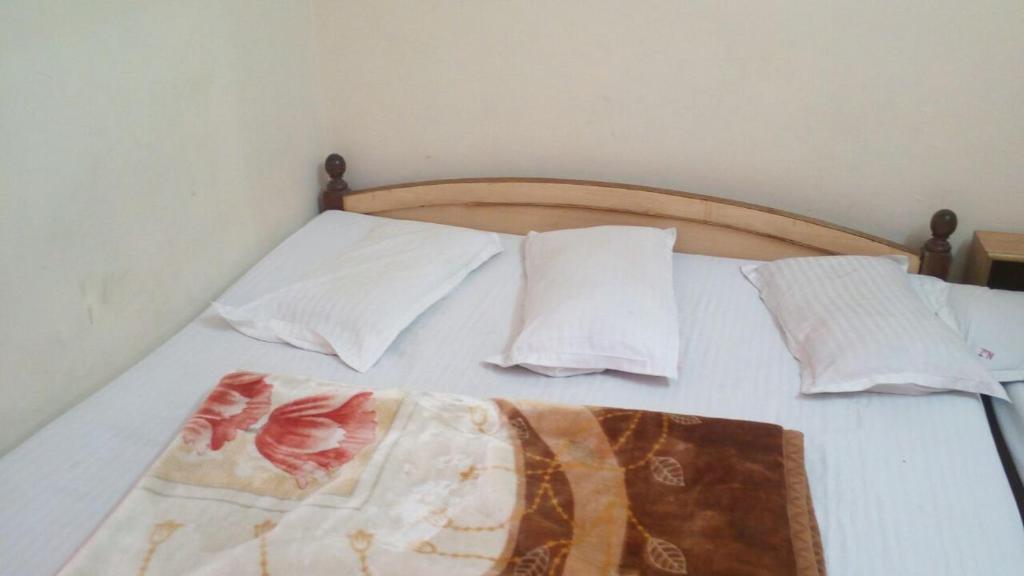 a bed with white sheets and pillows and avertisement at Hotel Patni Palace in Ajmer