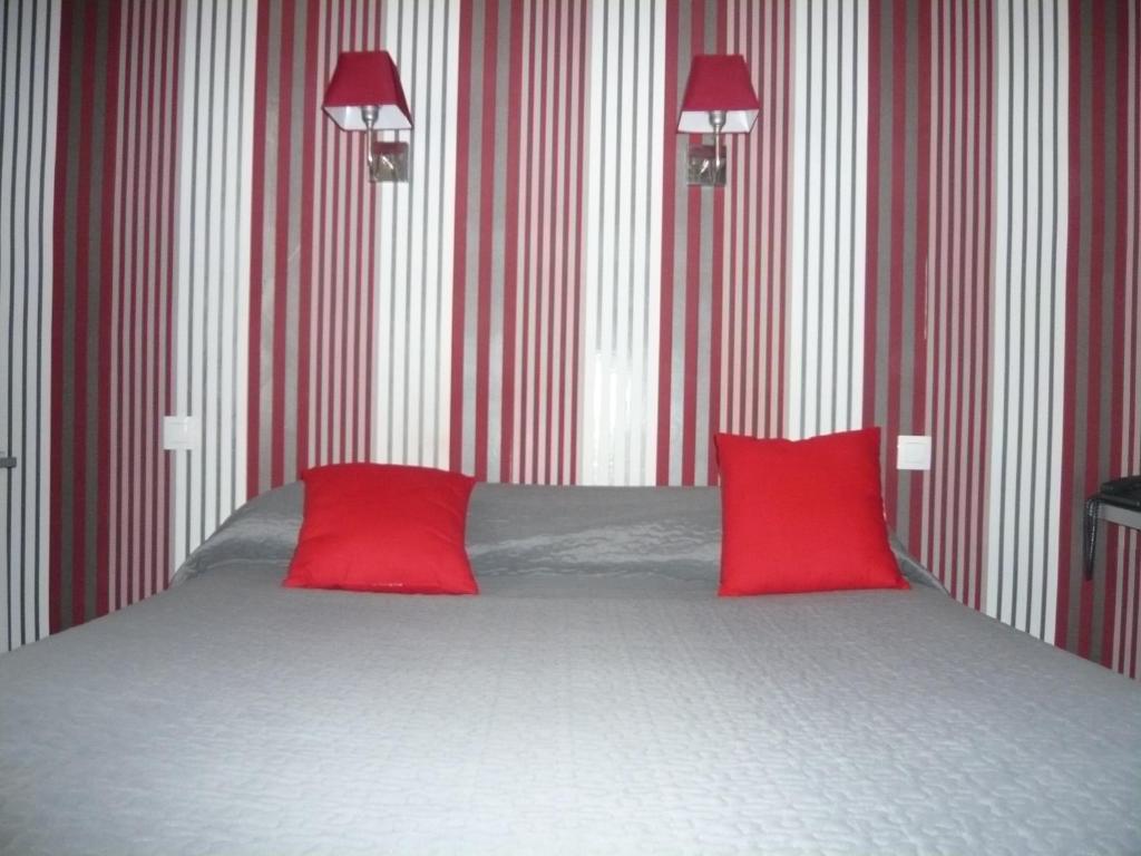 een slaapkamer met een bed met 2 rode kussens bij Hôtel - Restaurant Saint Jacques in Blois