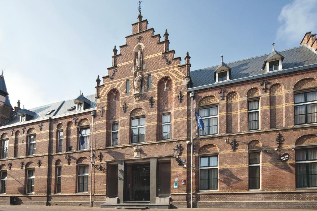 een groot bakstenen gebouw met een klokkentoren bij Fletcher Hotel Gilde in Deventer