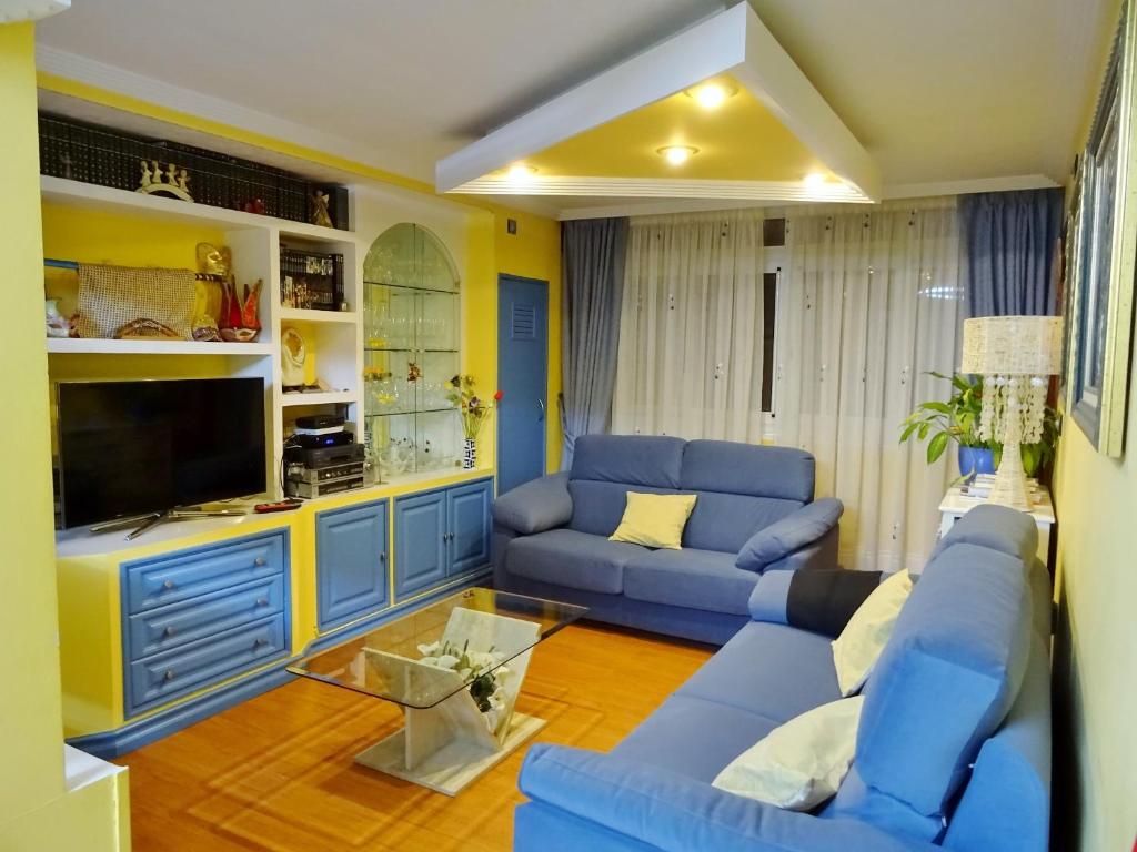 a living room with blue couches and a tv at Centro y playa in A Coruña