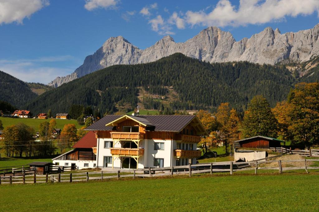 uma casa num campo com montanhas ao fundo em Luxus-Appartements Fosensteiner em Ramsau am Dachstein