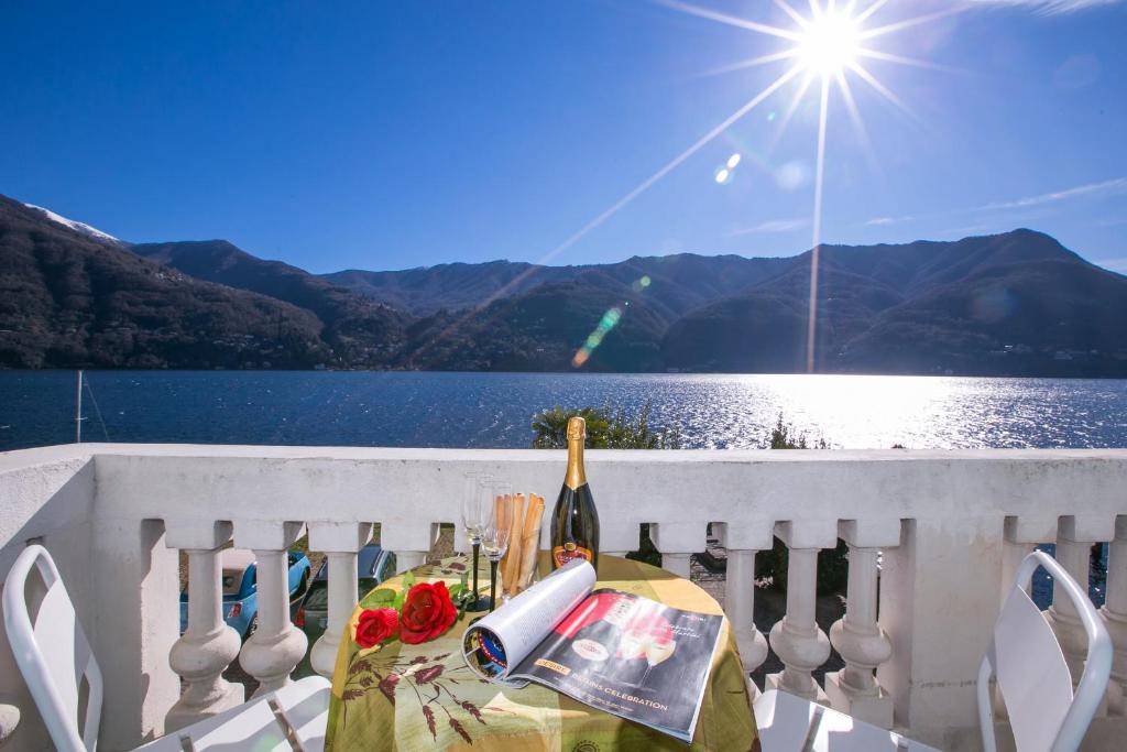 Carate UrioにあるVilla Larius Balconeのバルコニーにワイン1本と花を用意したテーブル