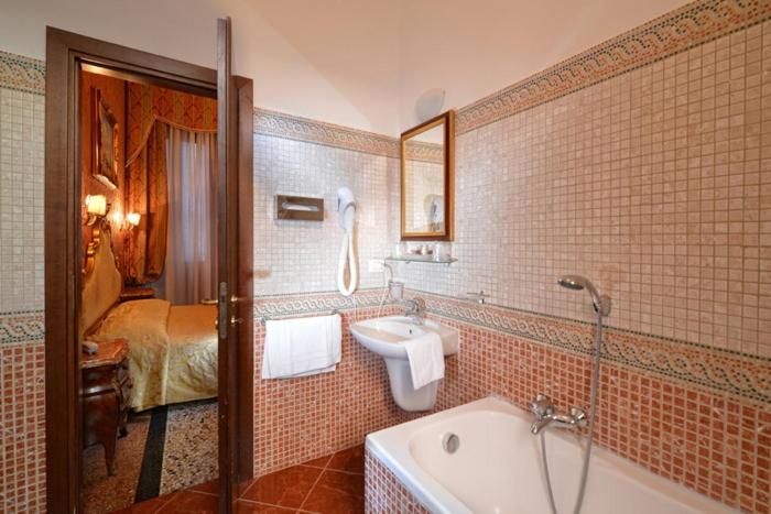 a bathroom with a tub and a sink and a bed at Residenza Hotel San Maurizio in Venice