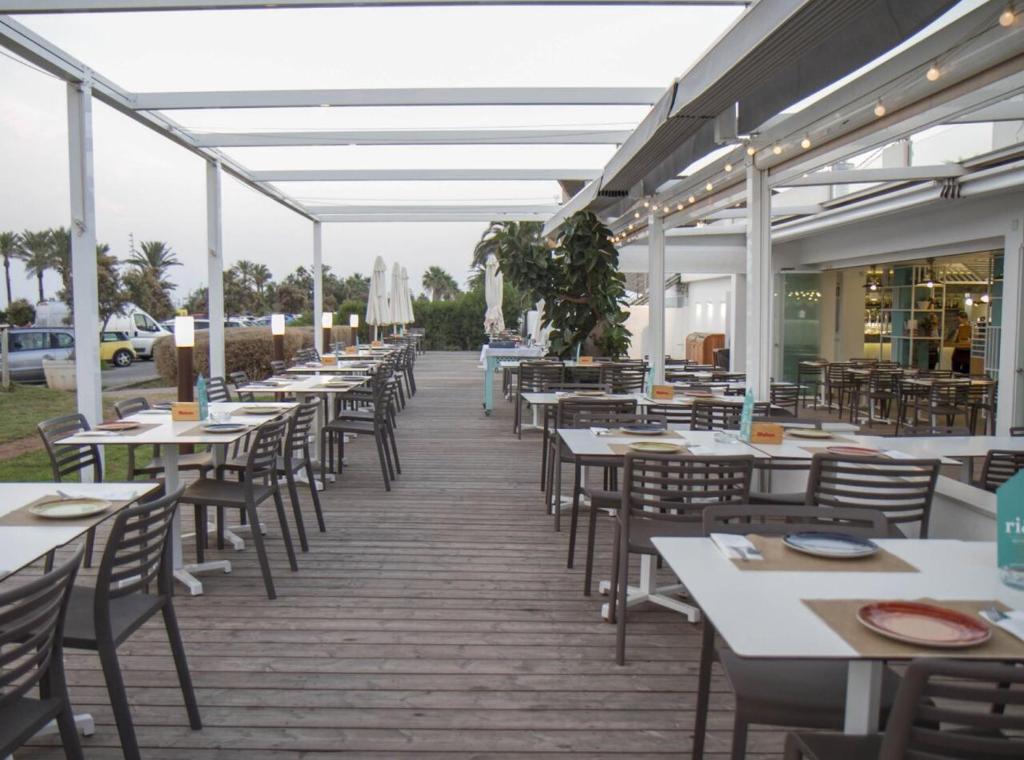 une rangée de tables et de chaises sur une terrasse dans l'établissement Golf & Playa a 1 min, à Grao de Castellón