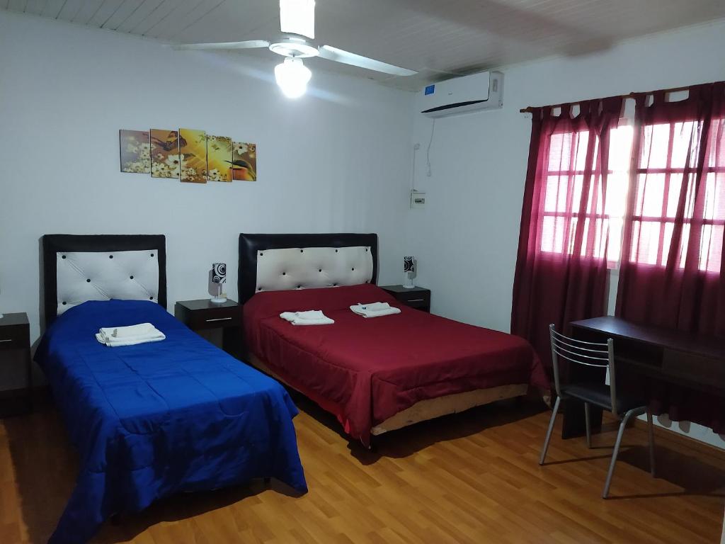 2 camas en una habitación con sábanas rojas y azules en PlazaApart 2 en Ramallo