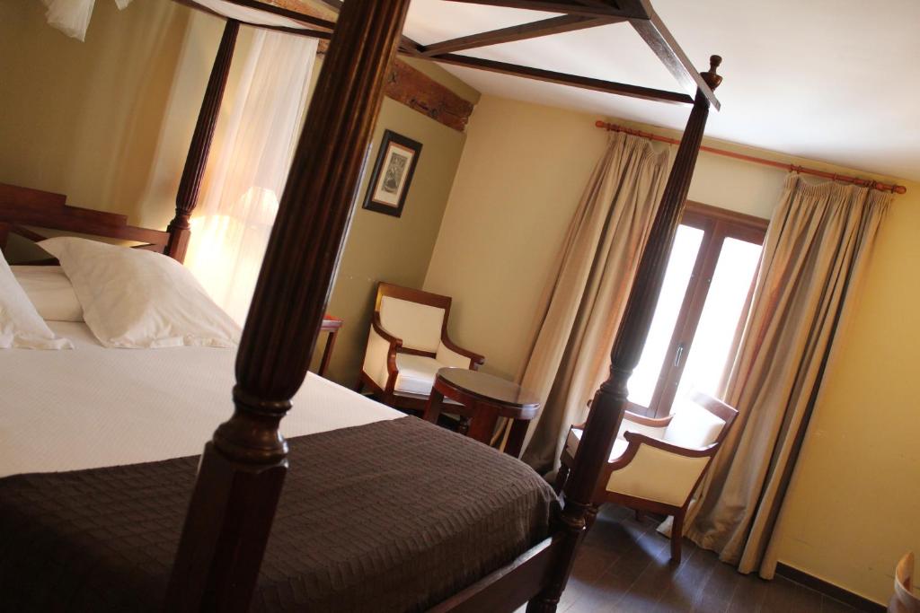 a bedroom with a four poster bed and a window at Hospedería de Cuenca in Cuenca