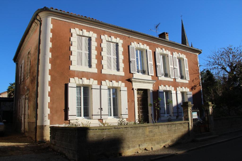ein altes Backsteingebäude mit weißen Fenstern auf einer Straße in der Unterkunft Les Chambres d'Eugénie in Poyanne