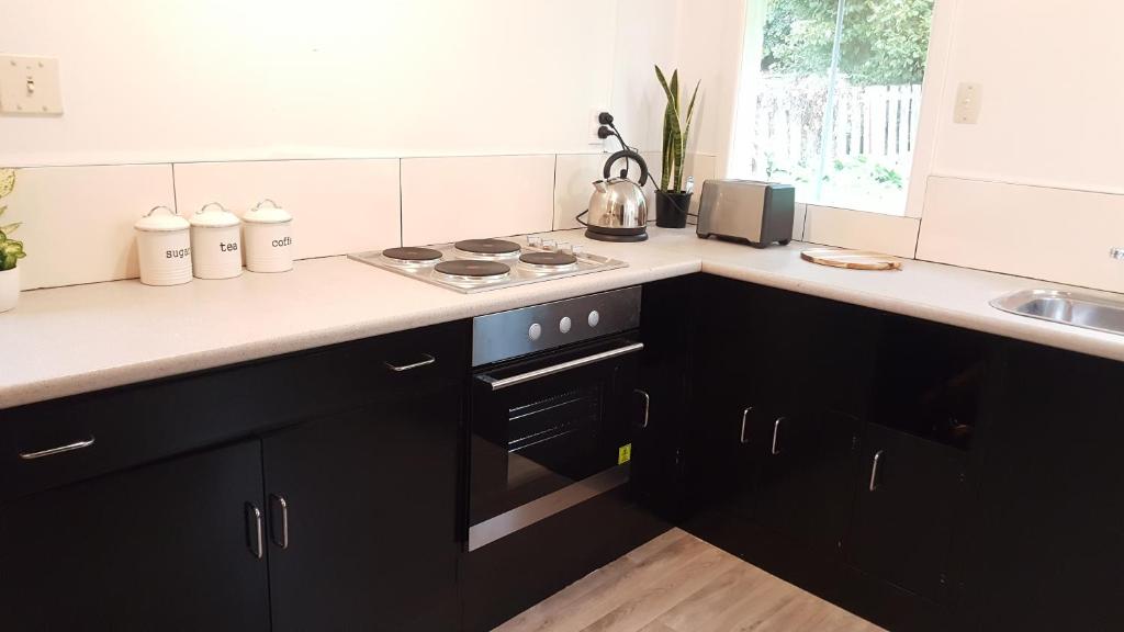 a kitchen with black cabinets and a stove top oven at Central Otago Cottage 4 bedroom in Roxburgh