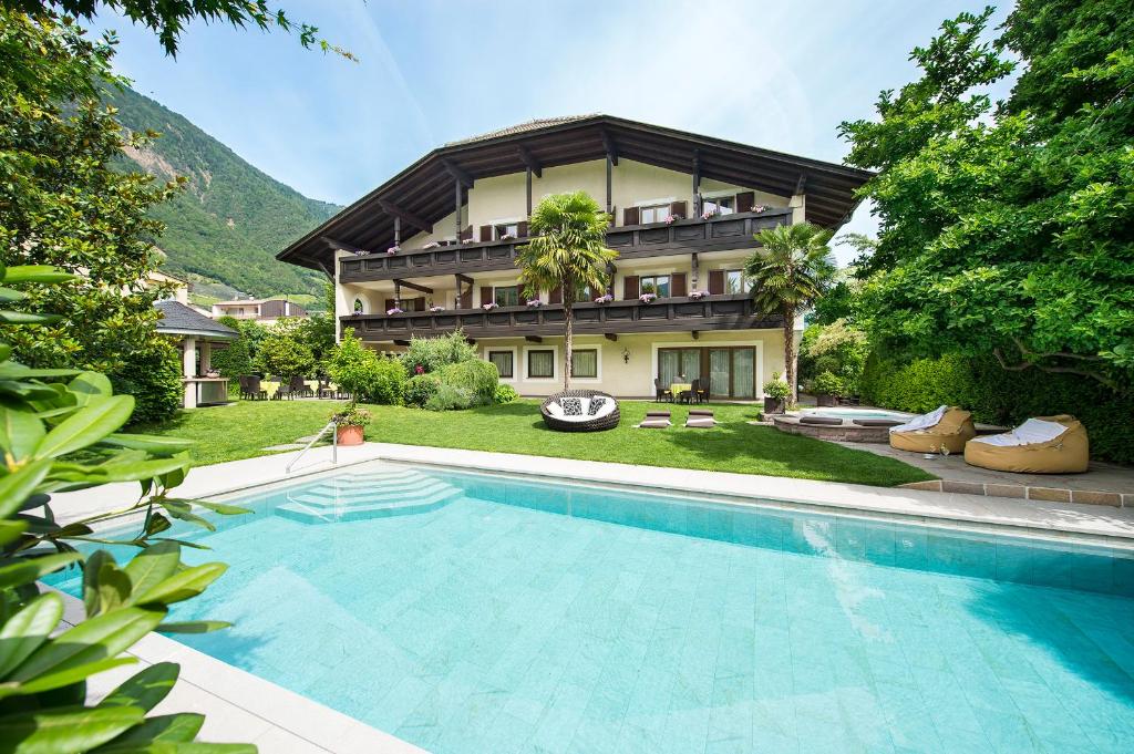 uma casa com piscina em frente a uma casa em Hotel Verena em Lana