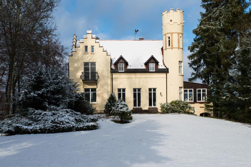 ein großes Haus mit einem Turm auf einem schneebedeckten Hof in der Unterkunft Schloss Suggenstein in Sigmaringen